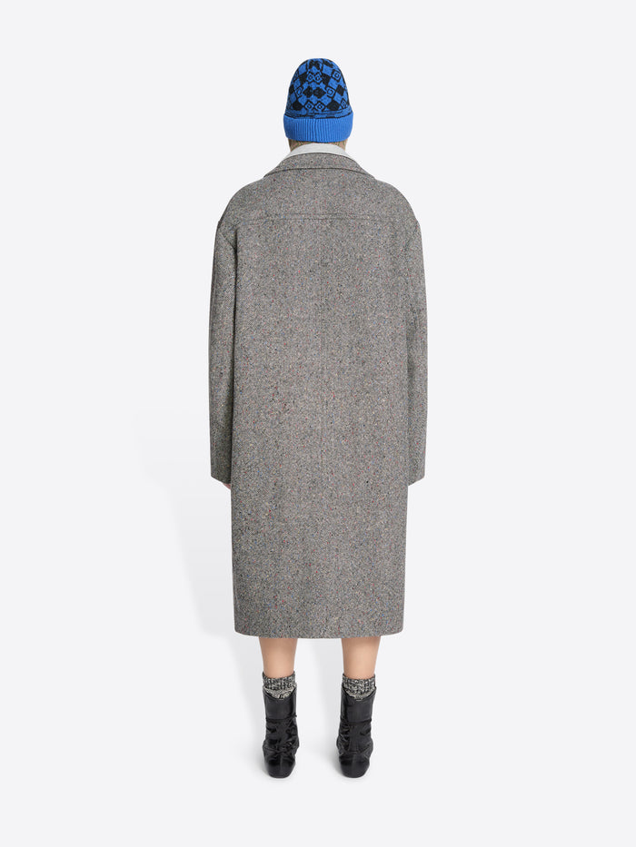 Back view of a person wearing a gray coat and blue beanie on a white background