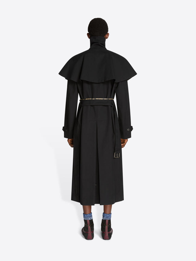 Back view of a person wearing a black long coat on a white background