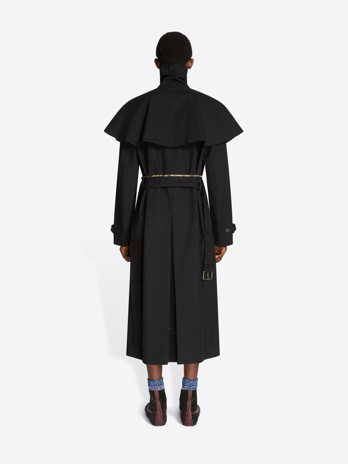 Back view of a person wearing a black long coat on a white background