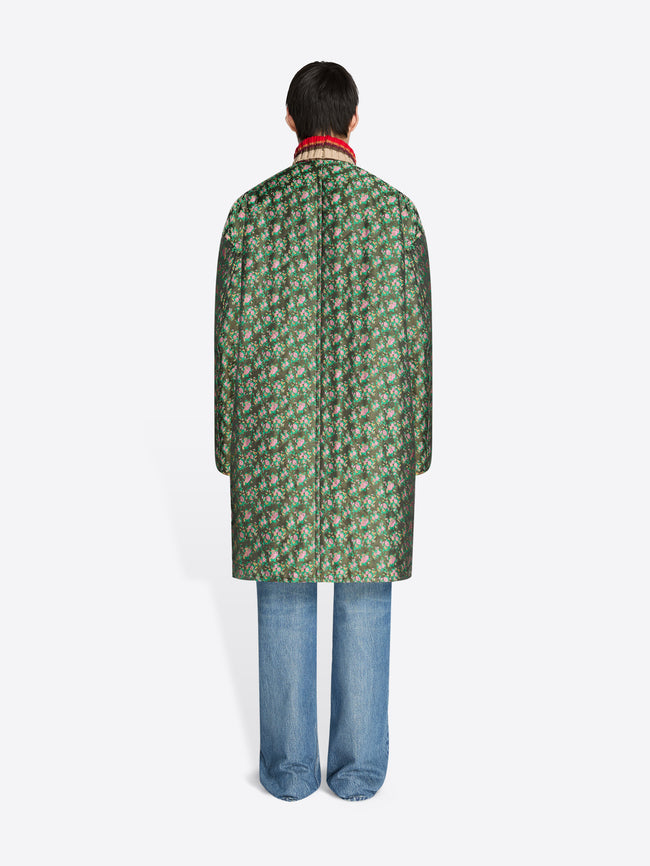 Person wearing a green patterned coat on a white background