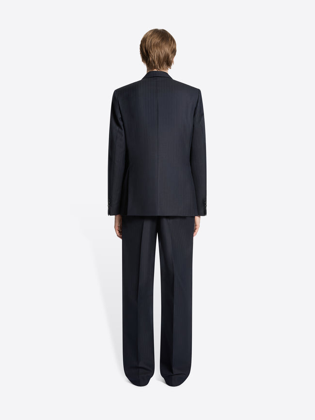 Back view of a person wearing a dark suit on a white background