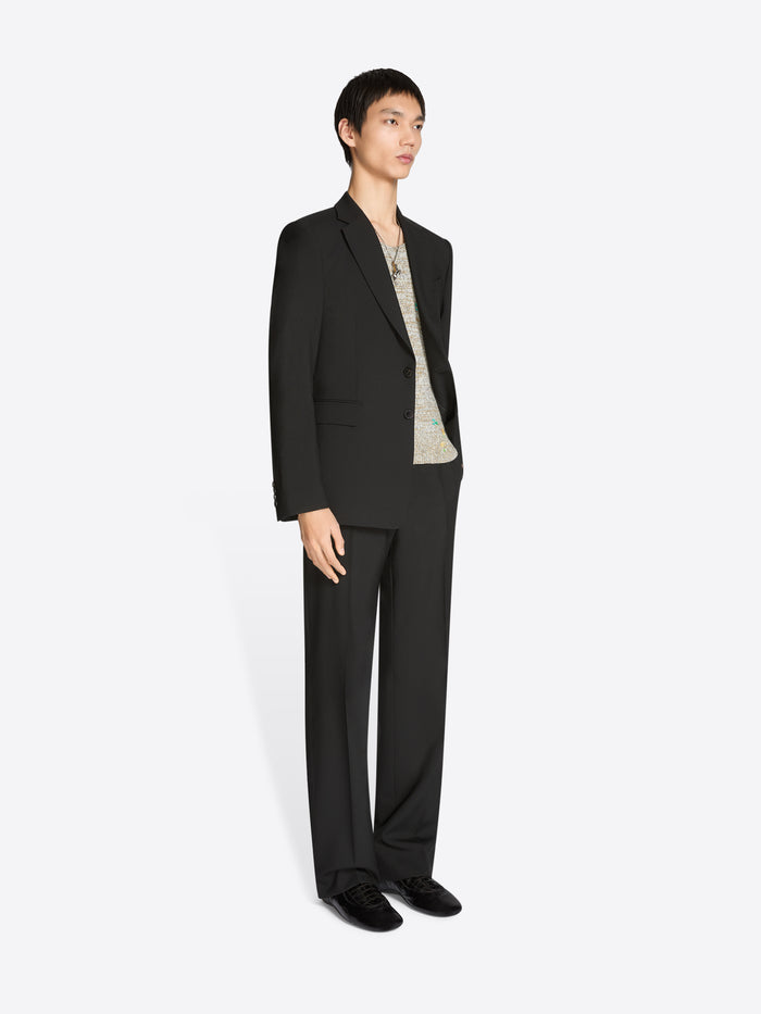 Person wearing a black suit with a yellow patterned scarf on a white background
