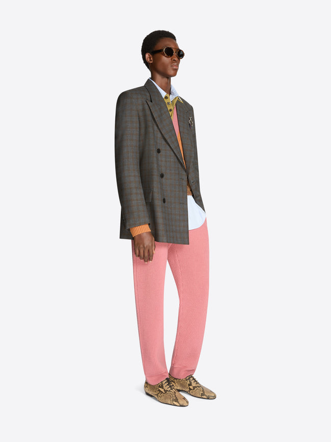 Person wearing a gray blazer, sweater, white shirt, pink pants, and shoes on a white background