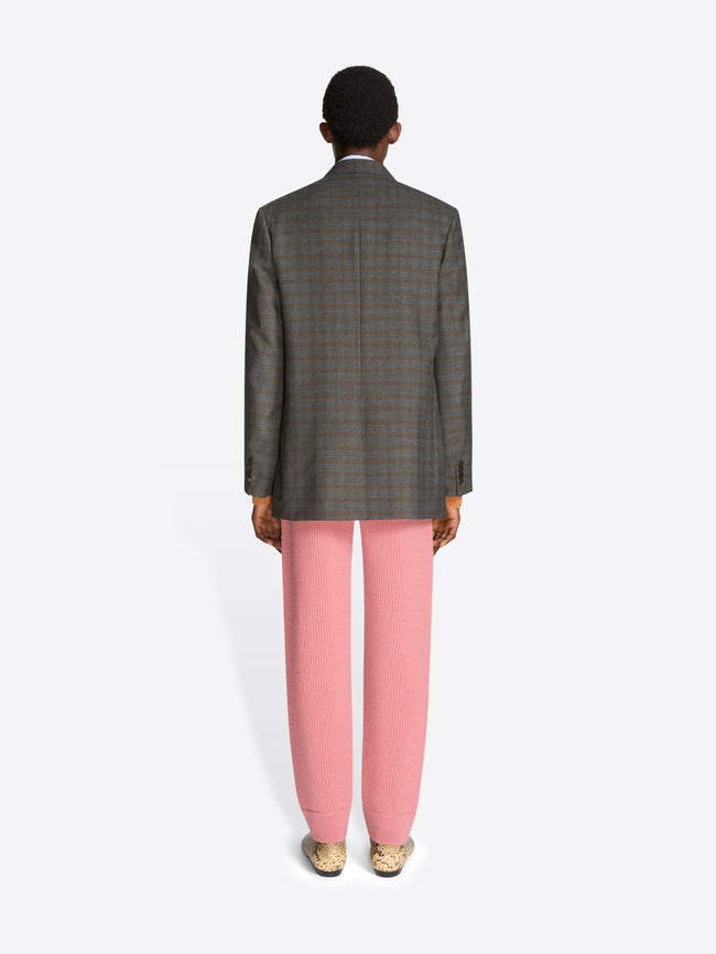 Back view of a man wearing a gray blazer, pink pants, and shoes on a white background