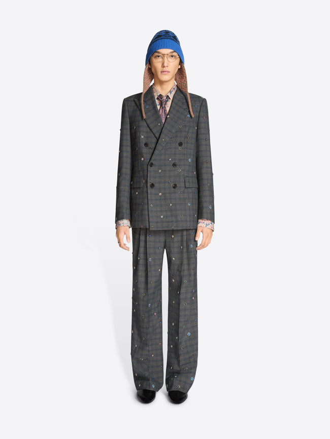 Person wearing a gray checkered suit and patterned hat on a white background