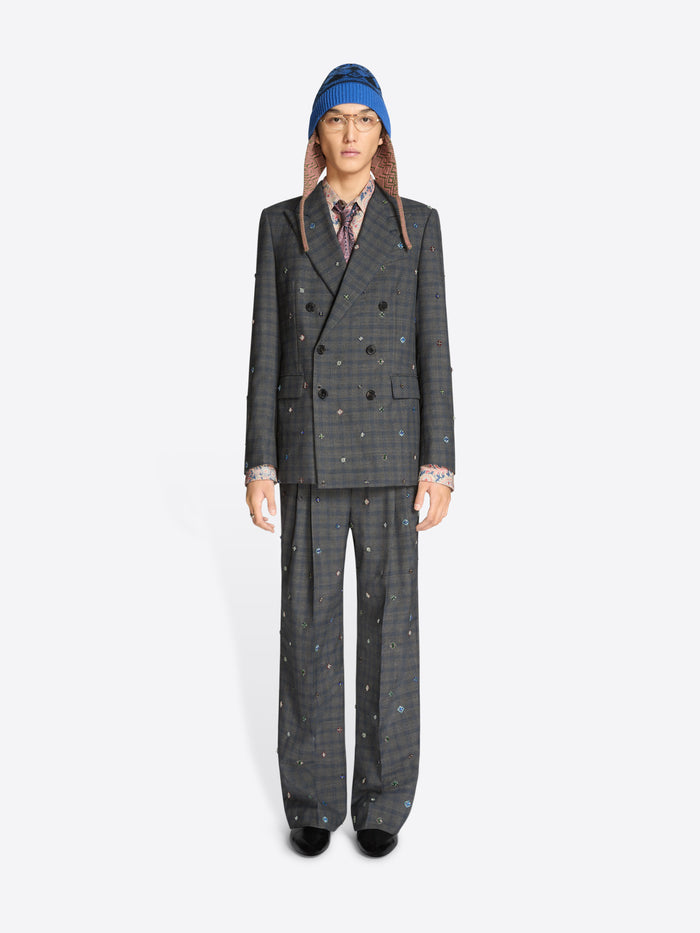 Person wearing a gray checkered suit and patterned hat on a white background
