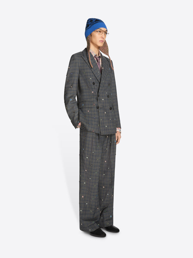 Person wearing a gray checkered suit and patterned hat on a white background