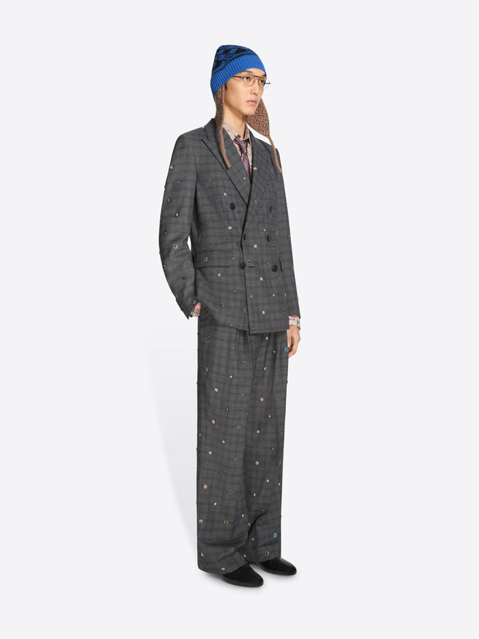 Person wearing a gray checkered suit and patterned hat on a white background