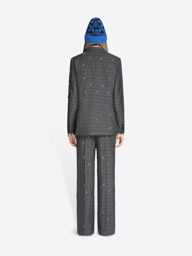 Back view of a person wearing a gray checkered suit and patterned hat on a white background