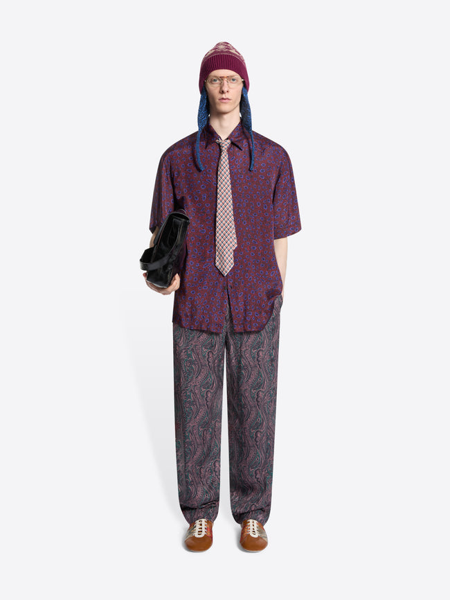 Person wearing a patterned shirt, pants and colorful hat on a white background