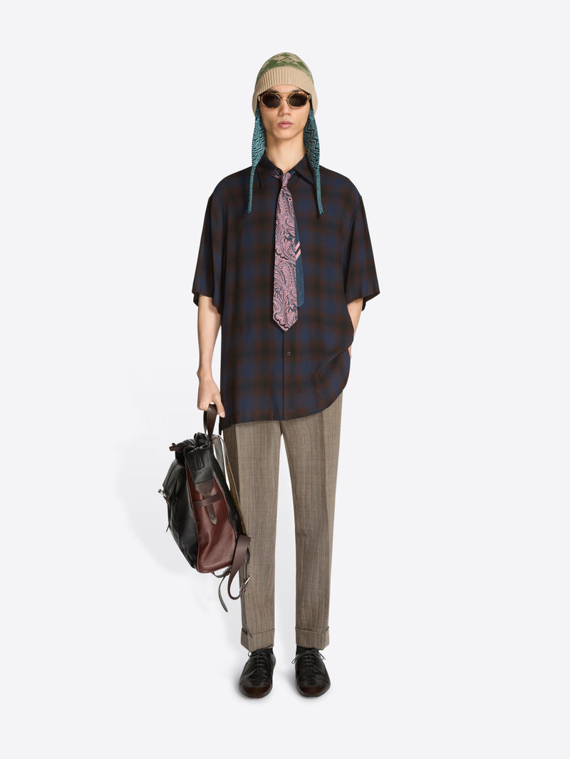 Person wearing a plaid shirt, tie, and sunglasses with a backpack on a white background