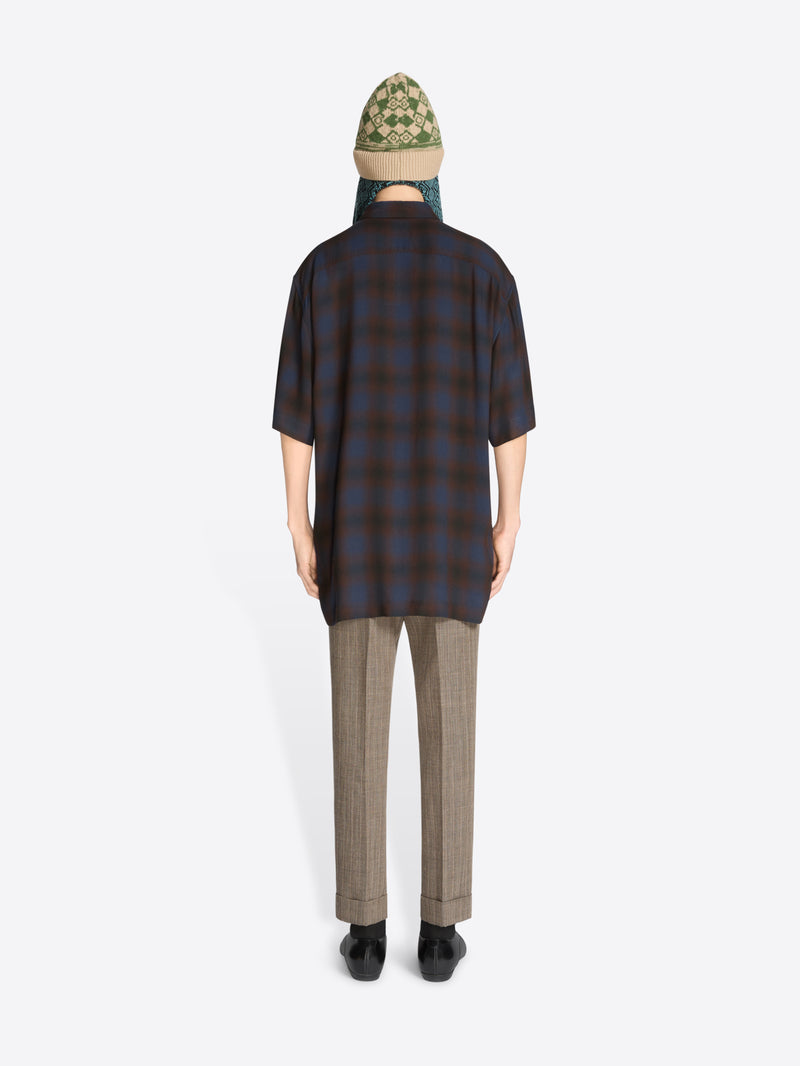 Person wearing a plaid shirt, tie, and sunglasses on a white background