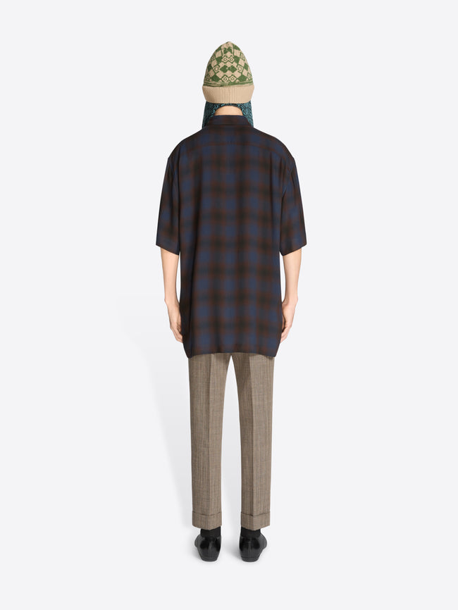 Person wearing a plaid shirt, tie, and sunglasses on a white background