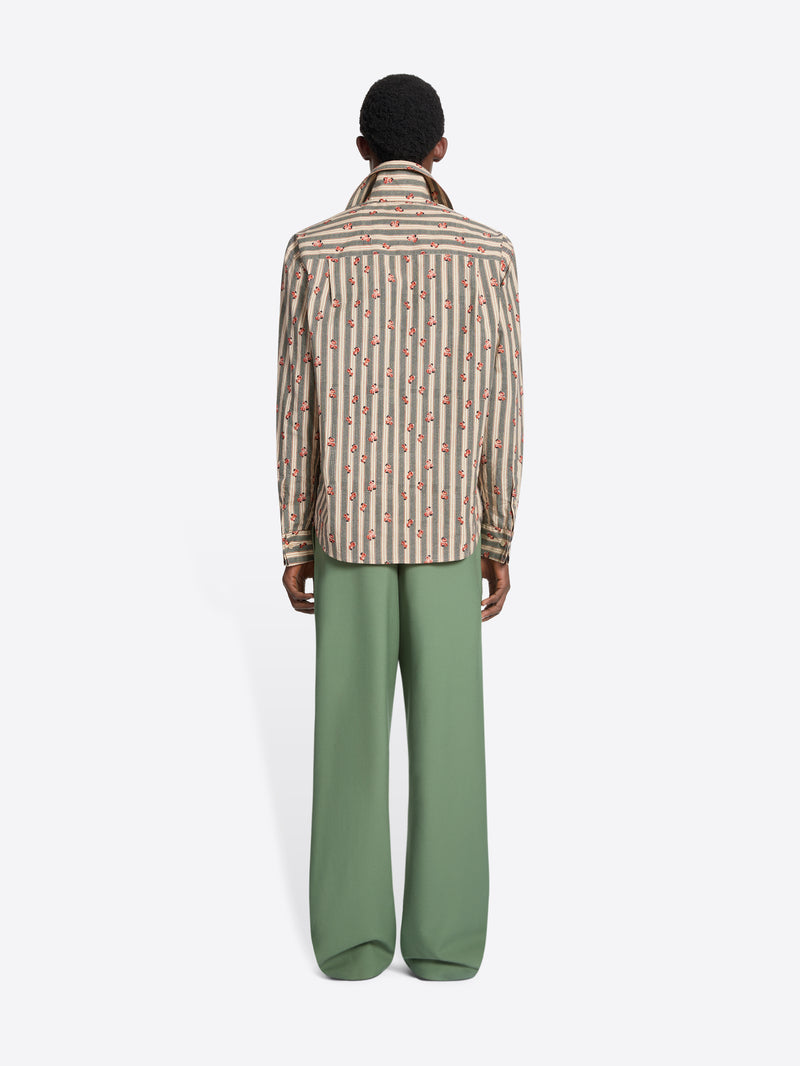 Back view of a person wearing a patterned shirt and green pants on a white background