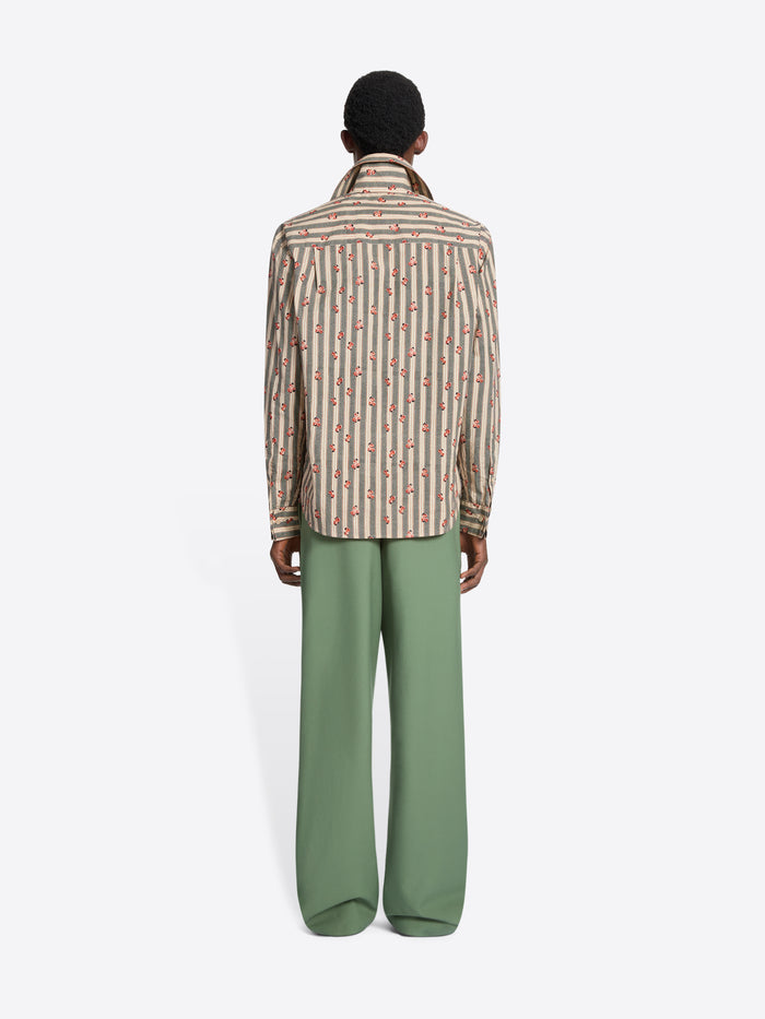 Back view of a person wearing a patterned shirt and green pants on a white background