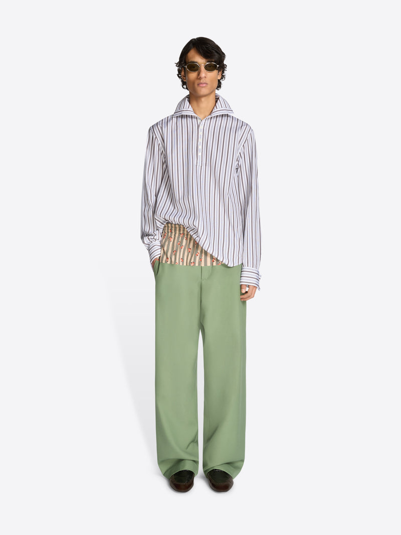 Person wearing a striped shirt and green pants on a white background