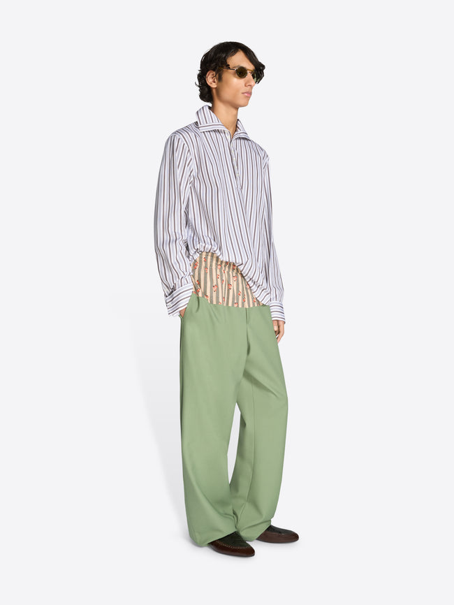 Person wearing a striped shirt and green pants on a white background