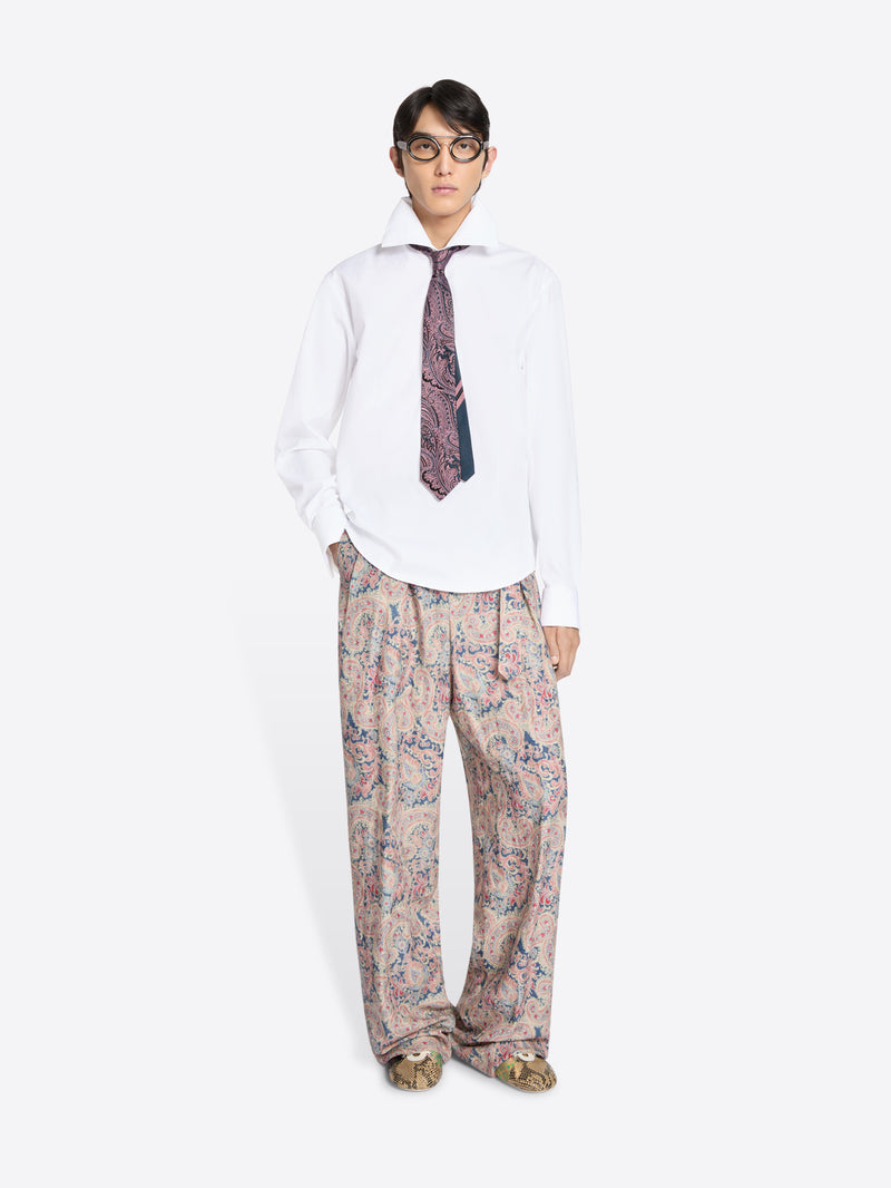 Person wearing a white shirt, patterned tie, and floral pants on a white background