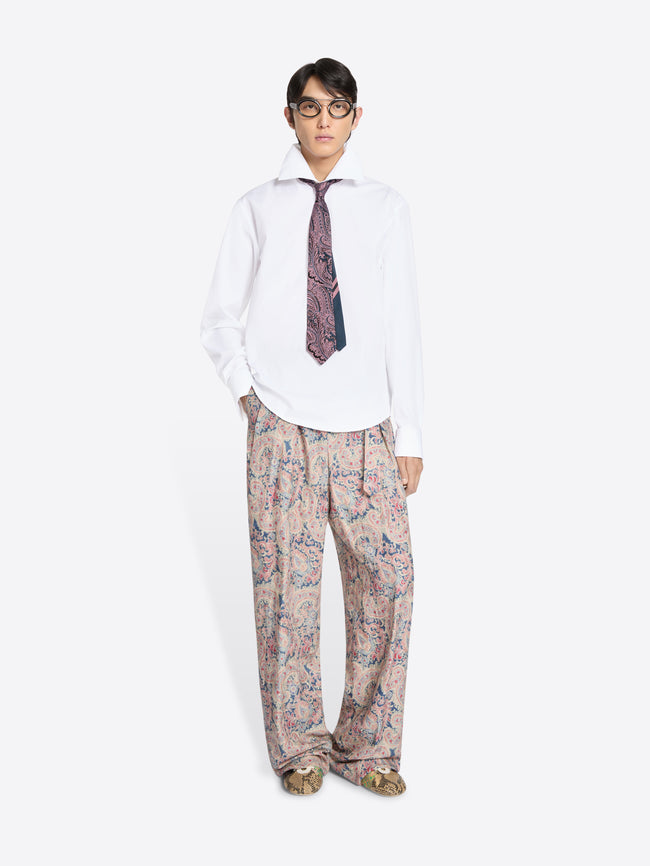 Person wearing a white shirt, patterned tie, and floral pants on a white background