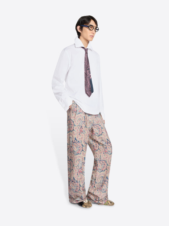 Person wearing a white shirt, patterned tie, and floral pants on a white background