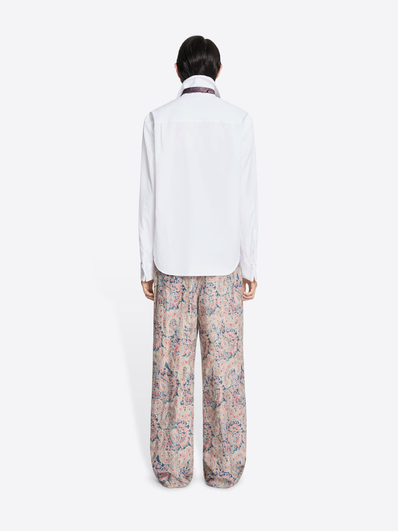Back view of a person wearing a white shirt and patterned pants on a white background