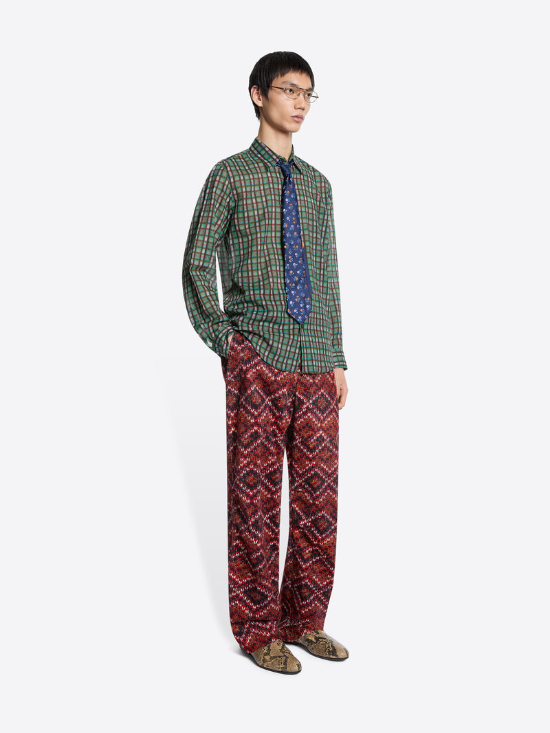 Person wearing a green checkered shirt and red patterned pants on a white background