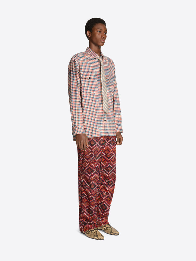 Person wearing a checkered shirt, tie and patterned pants on a white background
