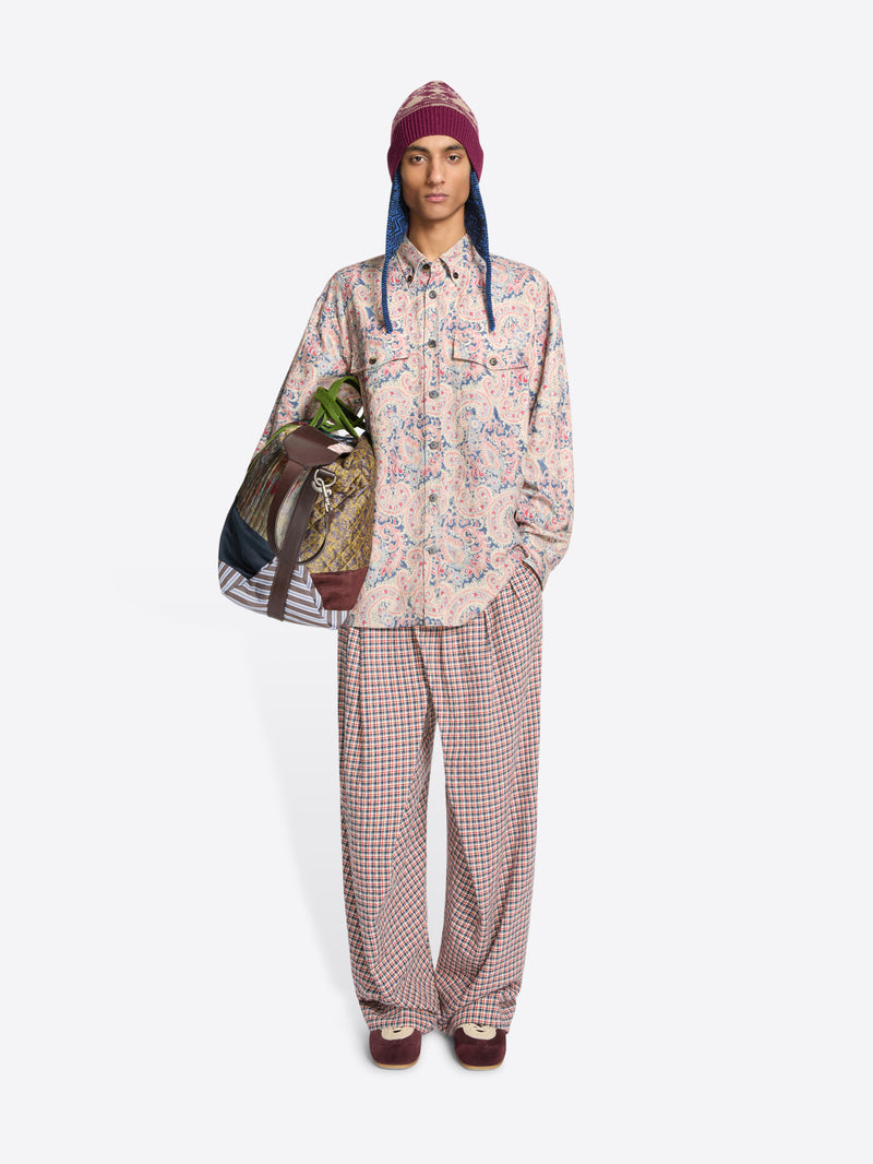 Person wearing a floral shirt and checkered pants with a colorful bag on a white background