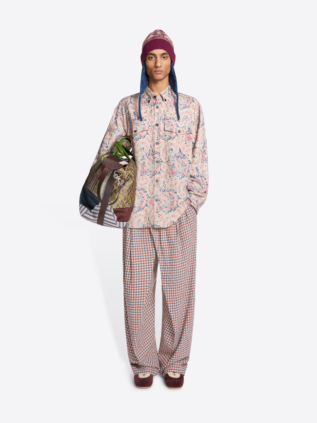Person wearing a floral shirt and checkered pants with a colorful bag on a white background