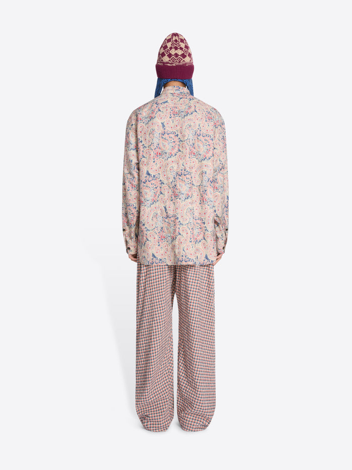 Back view of a person wearing a patterned shirt and checkered pants with a colorful hat on a white background