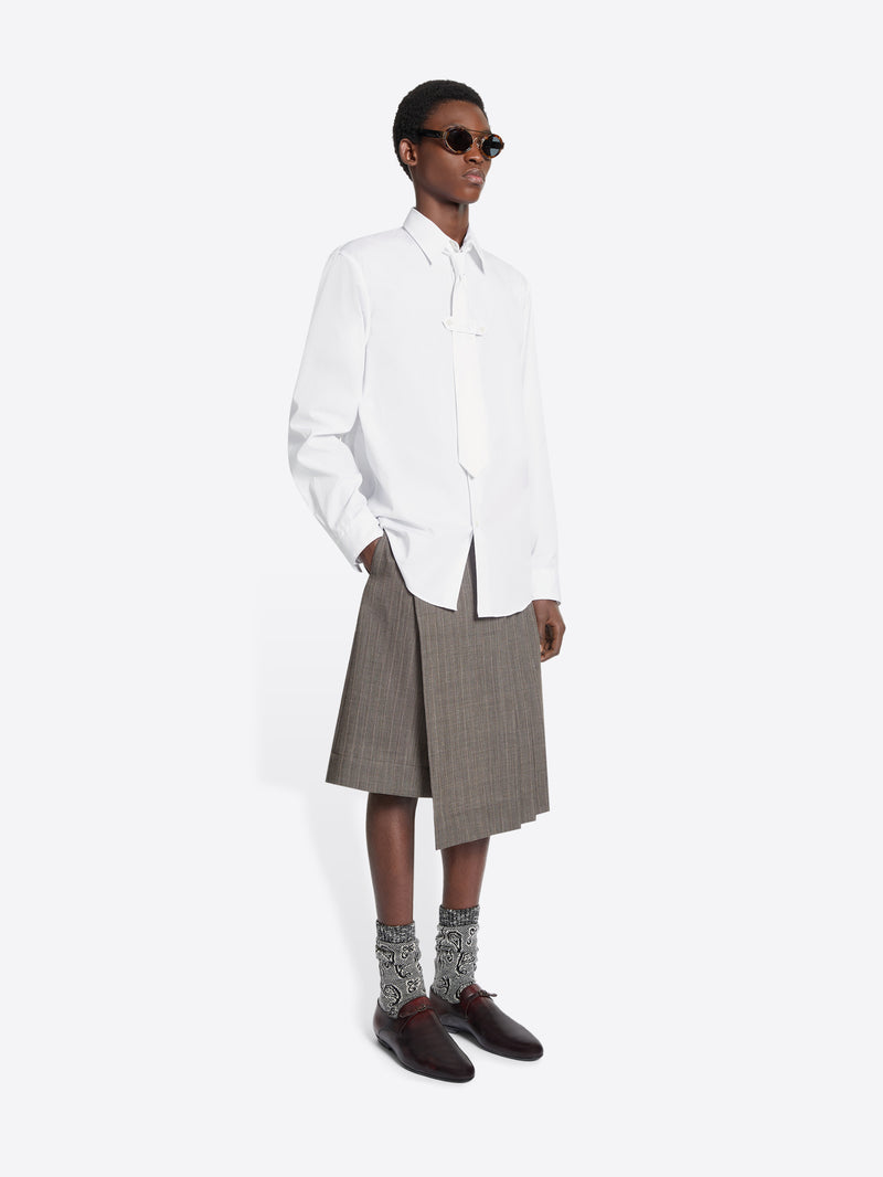 Person wearing a white shirt, gray skirt, and brown shoes on a white background