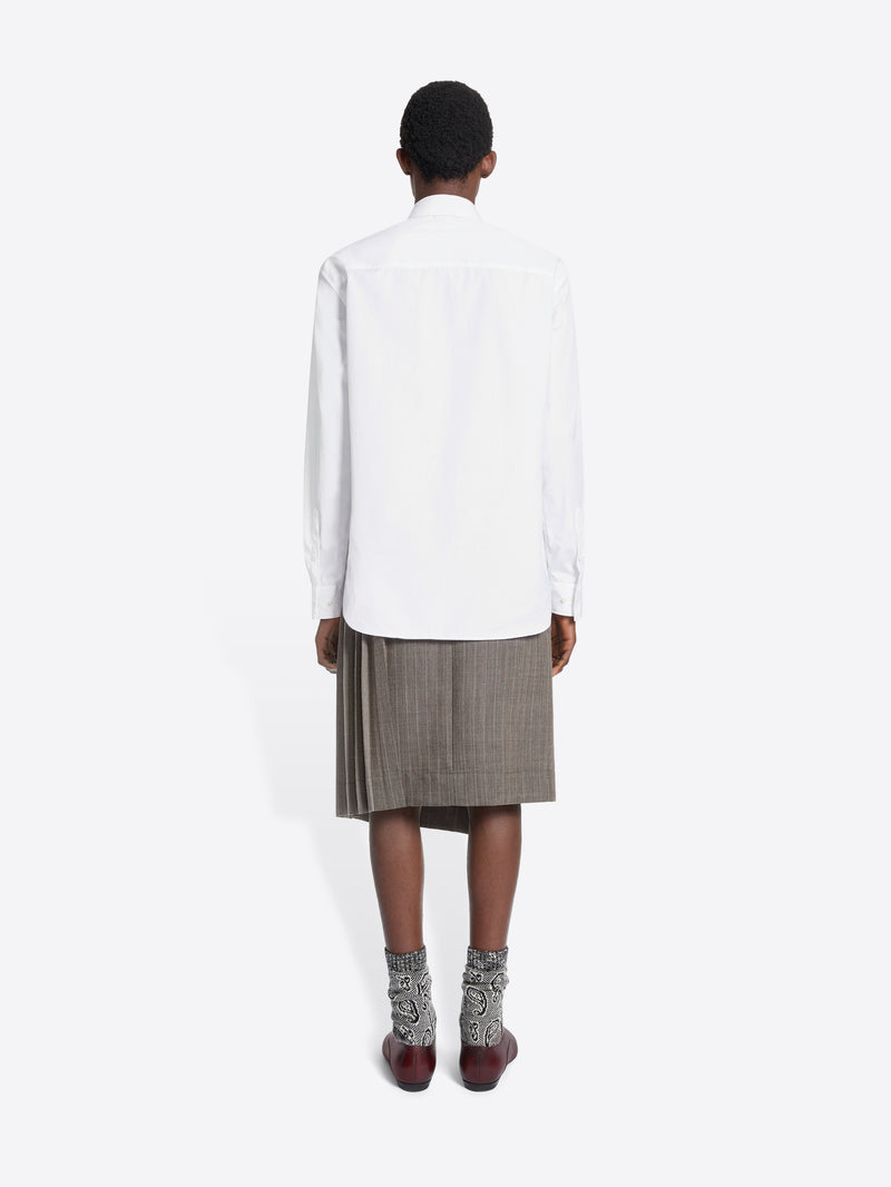 Person wearing a white shirt, gray skirt, and brown shoes on a white background