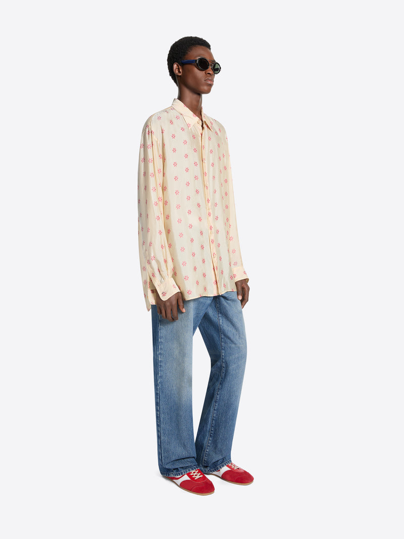 Person wearing a patterned shirt, jeans, and red shoes on a white background