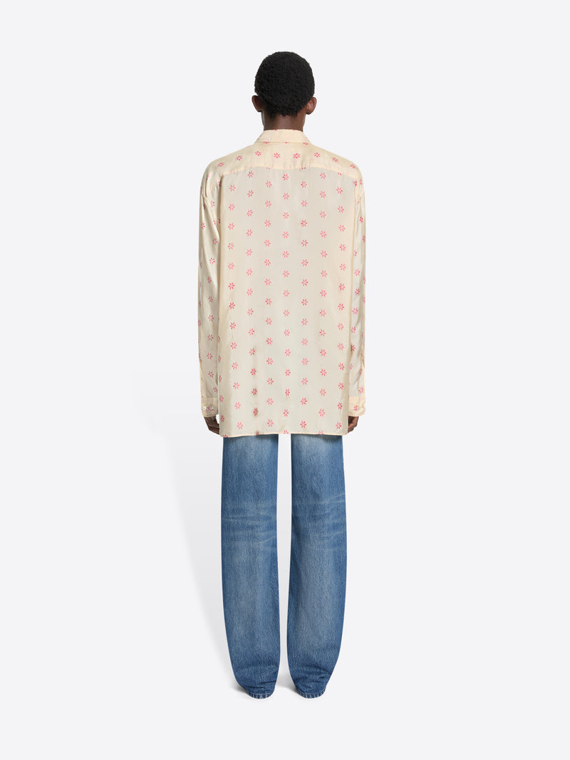 Back view of a person wearing a patterned shirt and blue jeans on a white background