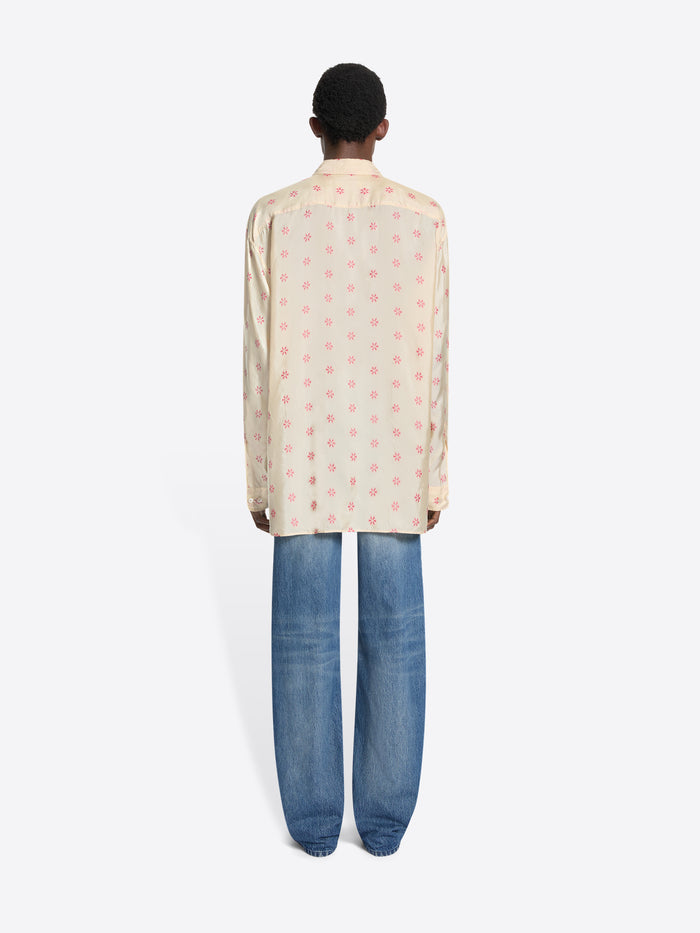 Back view of a person wearing a patterned shirt and blue jeans on a white background