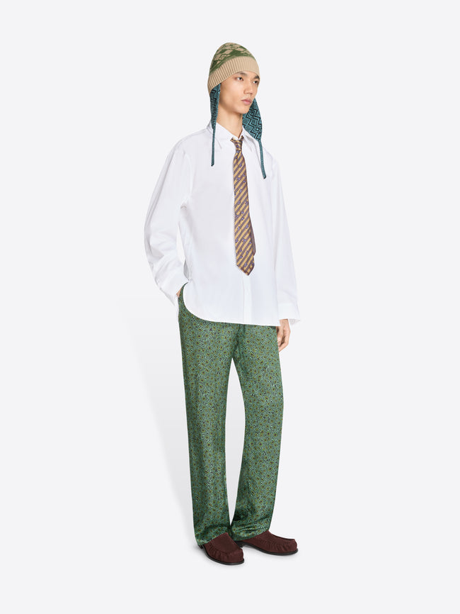 Person wearing a white shirt, green patterned pants, and a striped tie on a white background
