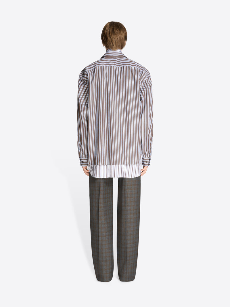Back view of a person wearing a striped shirt and checkered pants on a white background