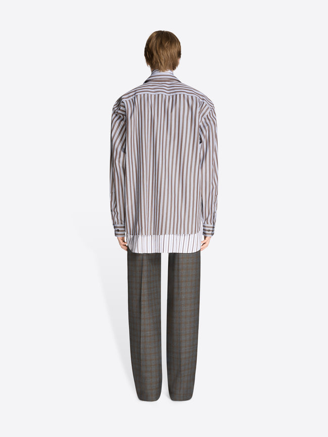 Back view of a person wearing a striped shirt and checkered pants on a white background