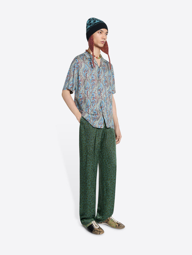 Person wearing a paisley-print short-sleeve shirt, patterned pants and a knit hat on the white background