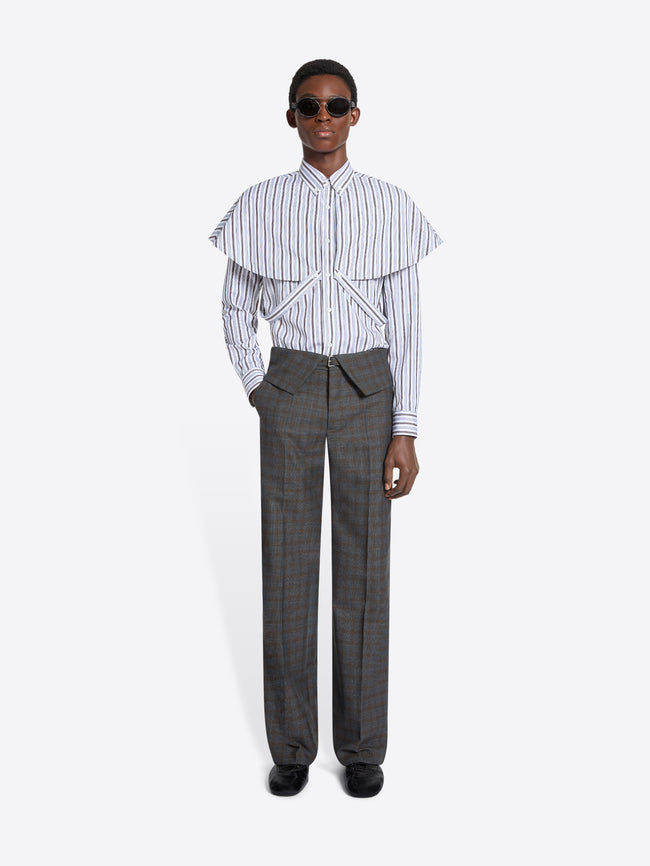 Person wearing a striped shirt with ruffled details and gray checkered pants on a white background