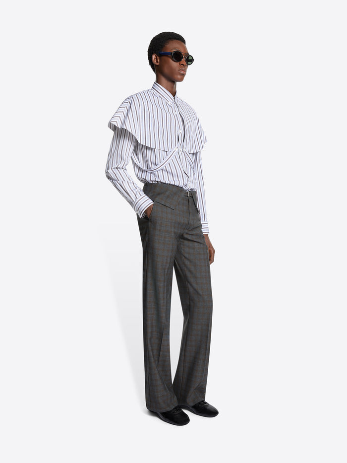 Person wearing a white ruffled shirt and gray checkered pants on a white background