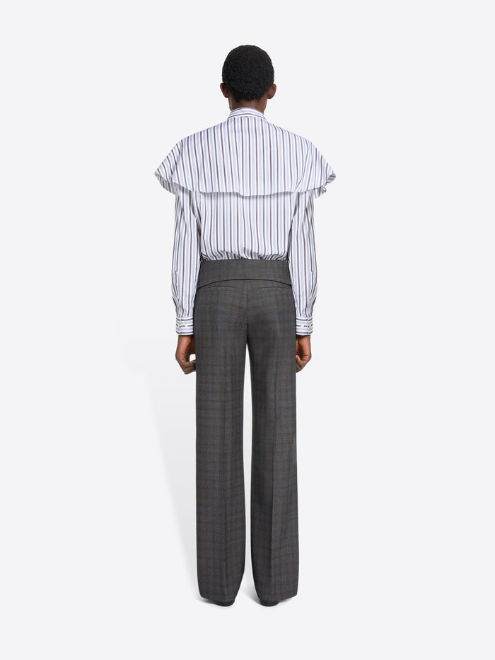 Back view of a person wearing a striped shirt and checkered pants on a white background
