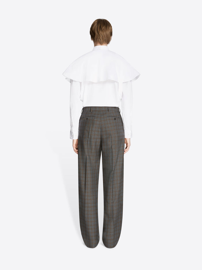 Back view of a person wearing a white shirt and gray checkered pants on a white background