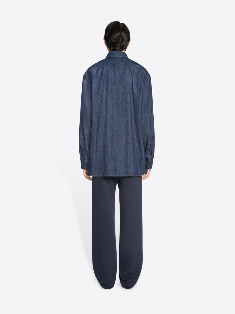 Person wearing a blue denim shirt and pants on a white background