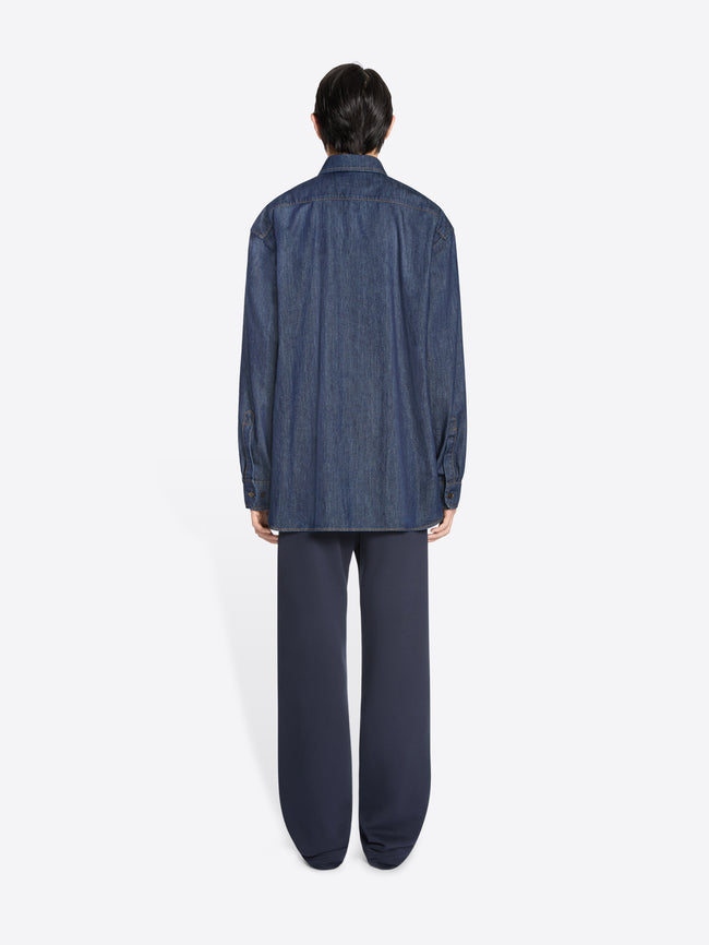 Person wearing a blue denim shirt and pants on a white background