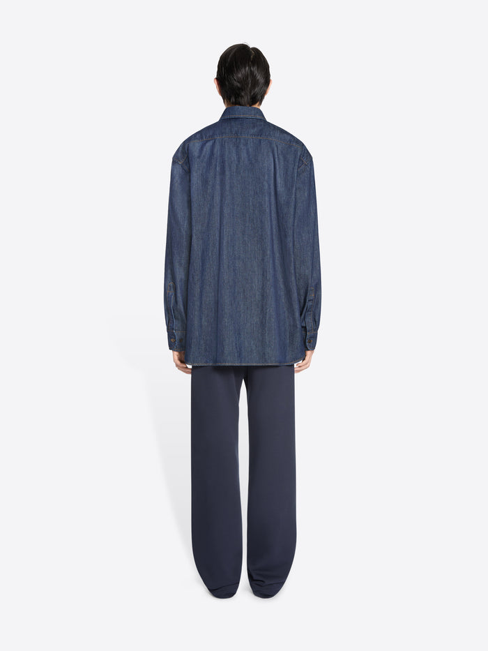 Person wearing a blue denim shirt and pants on a white background