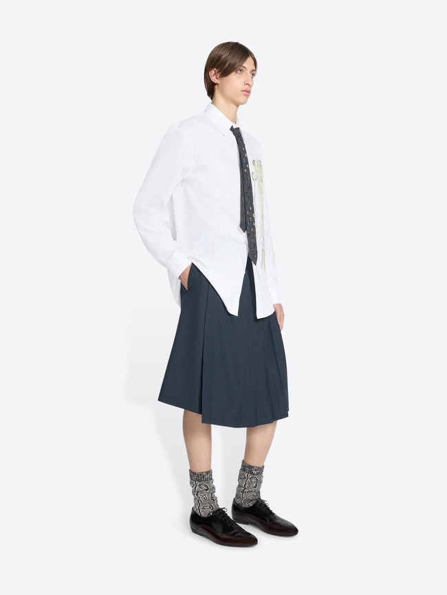 Person wearing a white shirt with a tie and dark skirt on a white background