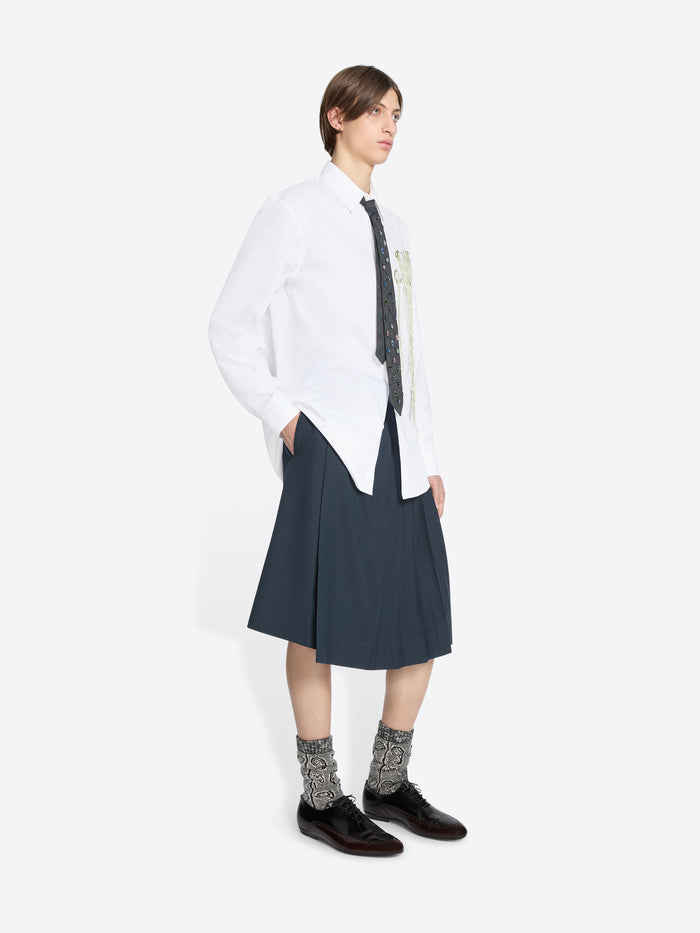 Person wearing a white shirt with a tie and dark skirt on a white background