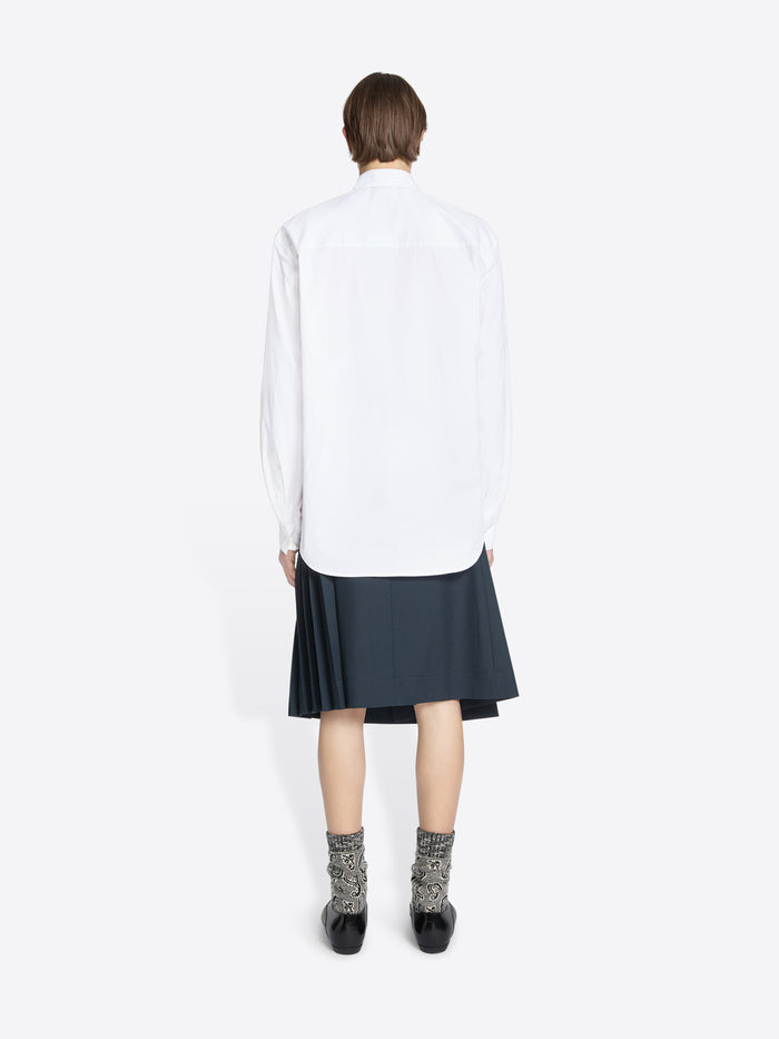 Back view of a person wearing a white shirt with a tie and dark skirt on a white background
