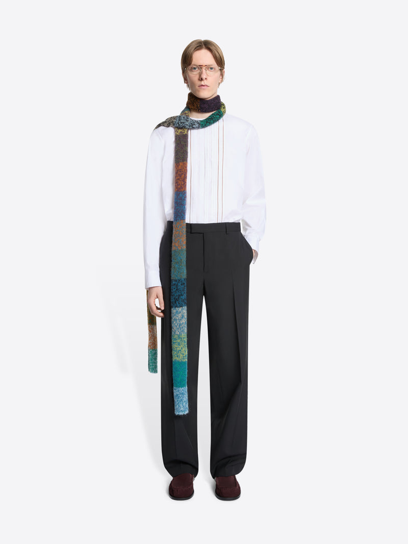 Person wearing a white shirt, black pants, and a colorful scarf on a white background